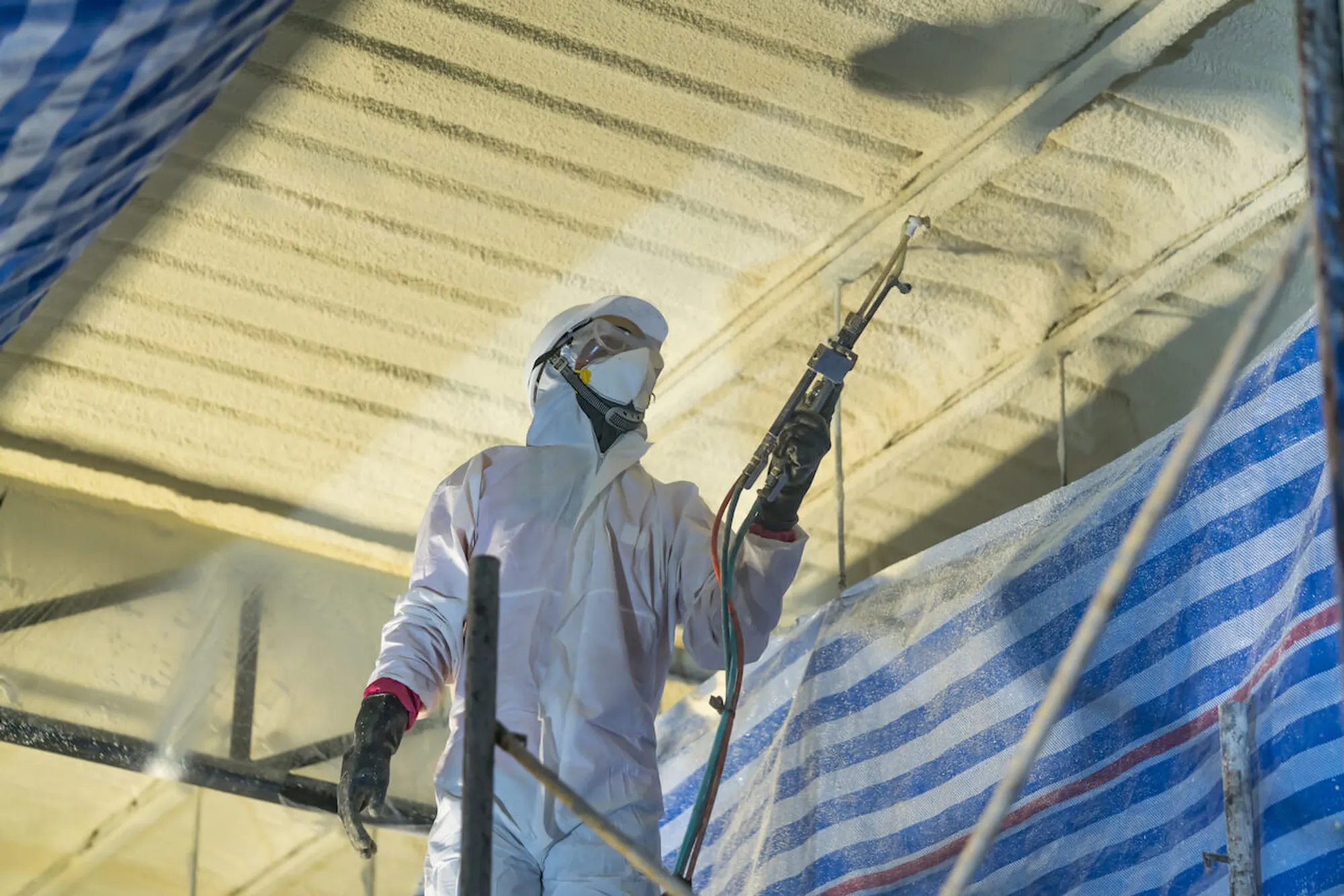 Bosela technician spraying closed-cell spray foam on an Alaska wall